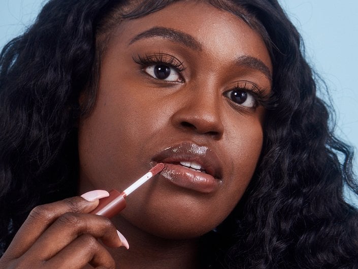 Close-up picture of a black model applying nude lip gloss