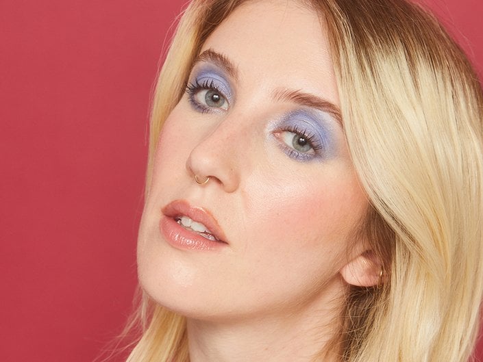 Picture of a person with blue eyes and blue eyeshadow on a red background