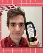 stephen holding up the Garnier Whole Blends Black Charcoal and Nigella Flower Oil Conditioner