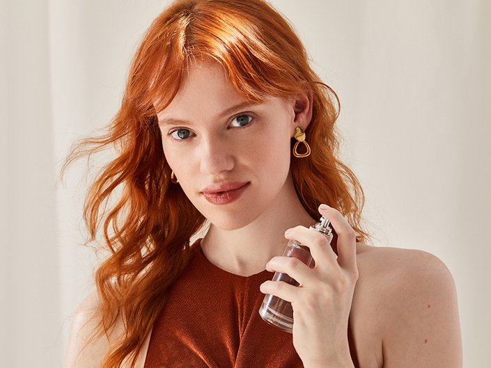 Picture of a red-haired model spraying perfume on their neck