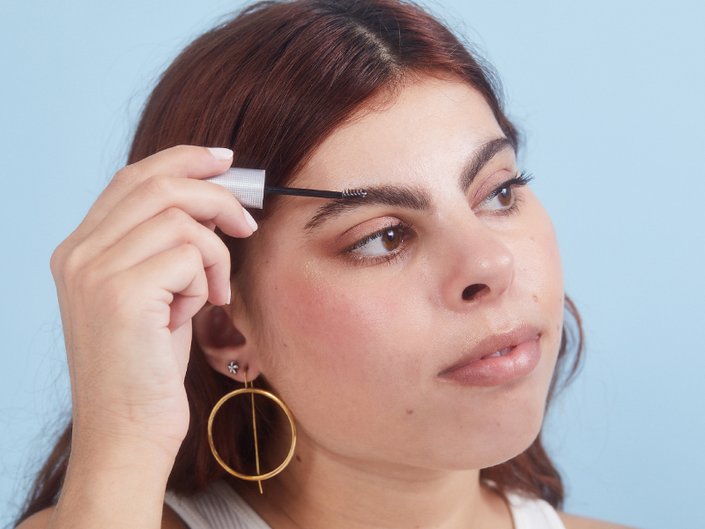 Picture of a person looking to the side while applying eyebrow gel