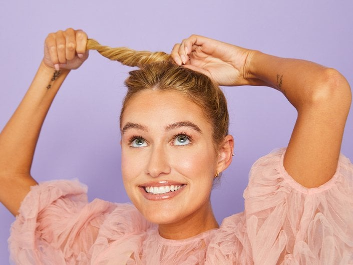 photo of person creating a messy bun on purple background
