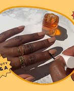 Image of a model painting her nails with cuticle oil on a yellow graphic background, with a text box that says "Beauty Q&A"